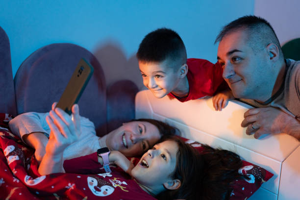 istock Happy family using smart phone at bedtime 1865928928