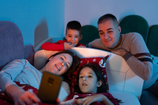 istock Happy family using smart phone at bedtime 1865929444