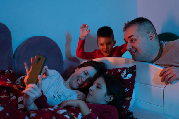 istock Happy family using smart phone at bedtime 1865929457