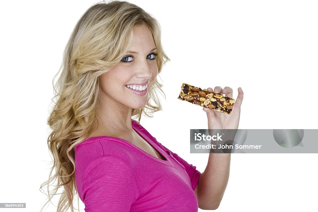 Woman eating a health bar Smiling woman eating a health bar and isolated on white background  Protein Bar Stock Photo