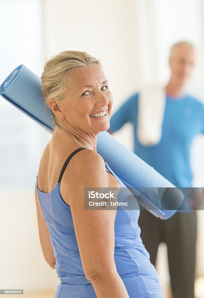 Senior Woman With Exercise Mat At Home Side view portrait of happy senior woman with exercise mat at home Exercising Stock Photo