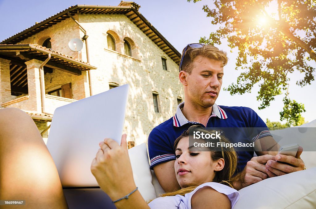 Молодая пара, используя мобильный телефон и портативный компьютер - Стоковые фото 18-19 лет роялти-фри