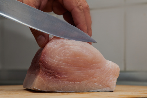 Cutting Fresh sword fish on wooden cooking desk