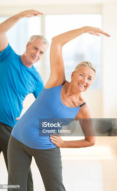 Couple Doing Stretching Exercise At Home Stock Photo - Download Image Now - 60-64 Years, 60-69 Years, Active Lifestyle