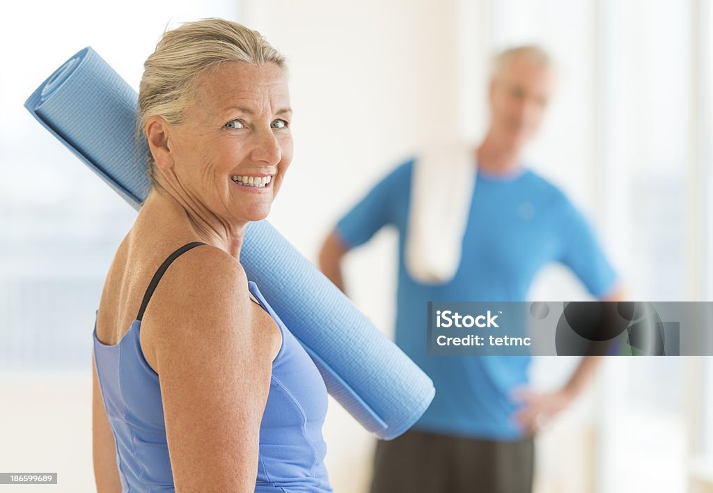 Smiling Woman With Exercise Mat At Home Side view portrait of smiling senior woman with exercise mat at home Exercise Mat Stock Photo