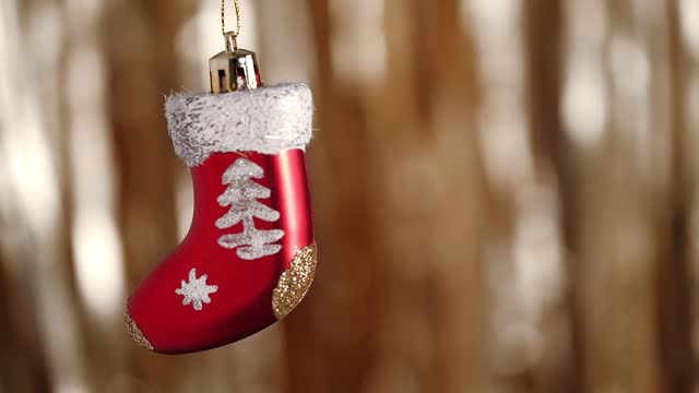 close up cute Christmas bauble in form red Santa Claus stocking on background festive lights.