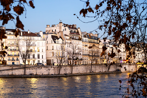 Facade of a Parisian buildings on Seine quayside, in winter, with golden light. View on île Saint Louis (Saint Louis island), in Paris, France. December 16, 2023.