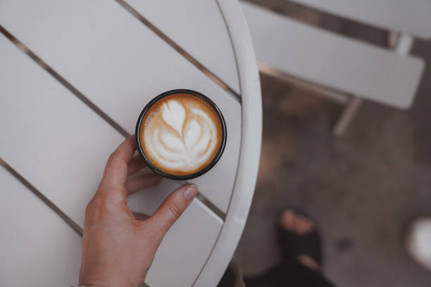 istock Cappuccino coffee in woman's hand from above 1866043096