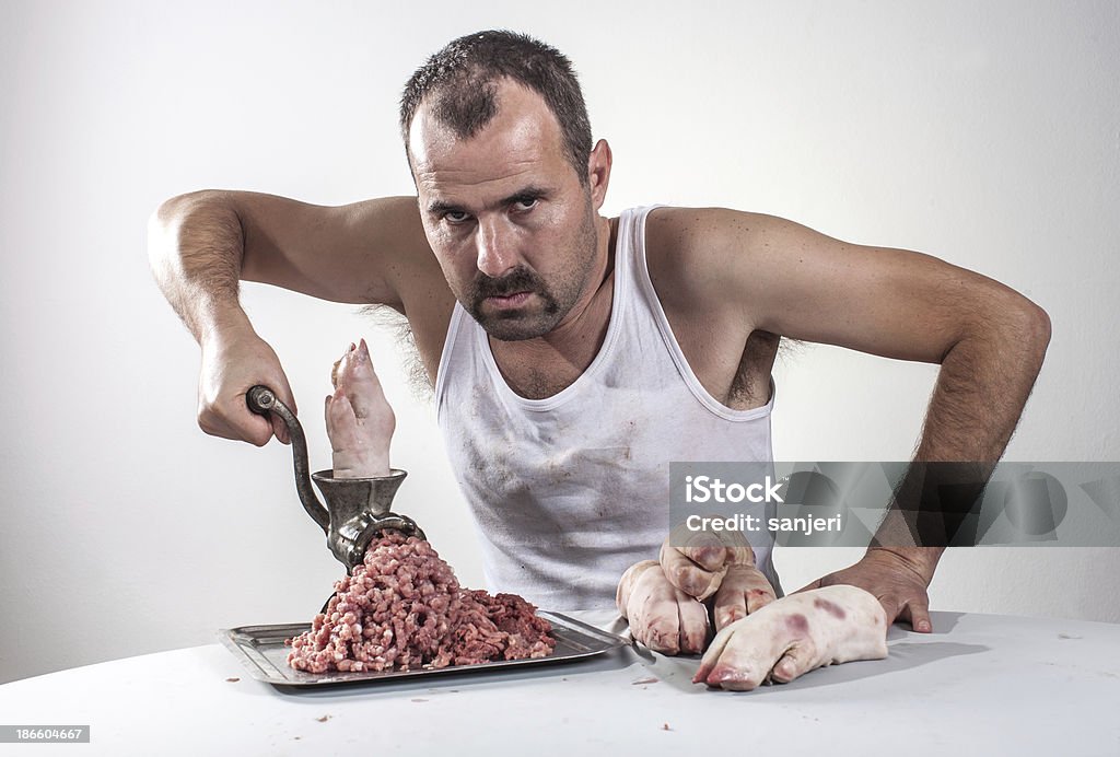 Crazy açougueiro com carne suína atrás da mesa - Foto de stock de Animal morto royalty-free