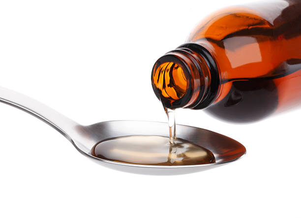 Bottle pouring Medicine Syrup in Spoon stock photo