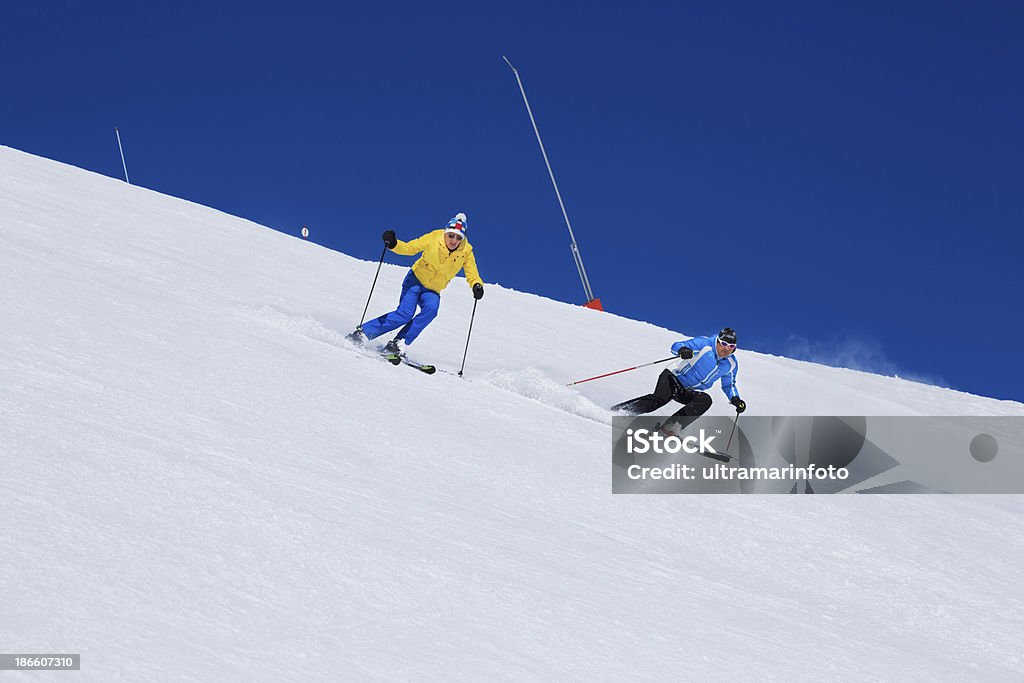 Skiing - Winter Sport Best Friends. Snow skiers, skiing carving at high speed, mountain ski resort in the snowy Alps. Active Lifestyle Stock Photo