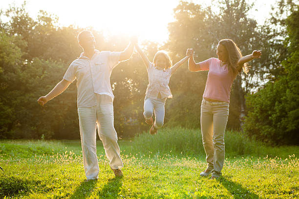 istock Mother and father playing with daughter in park . 186607324