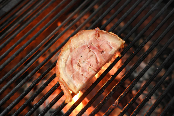 bacon pork rinds roasting on a charcoal barbecue lit wood with fire for roasting pork pancetta on the grill taste