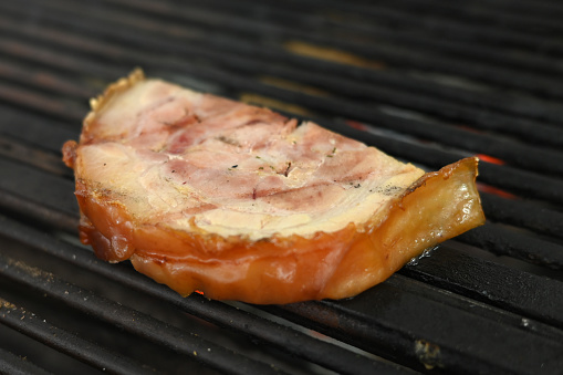 bacon pork rinds roasting on a charcoal barbecue lit wood with fire for roasting pork pancetta on the grill taste