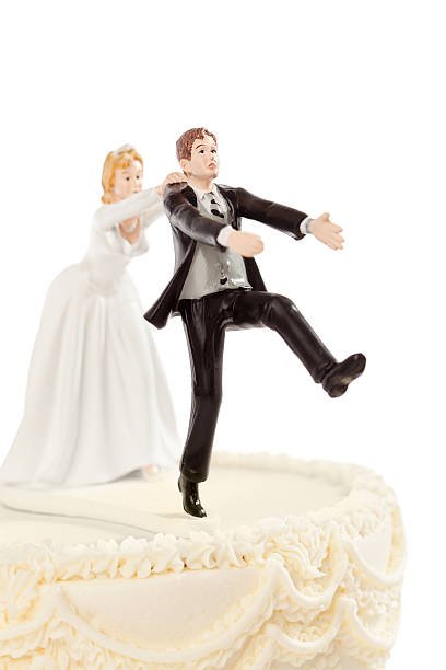 Bride Chasing Groom Humorous Wedding Cake Topper on White Subject: A humorous wedding cake figurines with the bride chasing and catching the terrified groom in the act of escape. wedding cake close up macro stock pictures, royalty-free photos & images