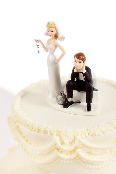 Marriage Ball and Chain Humorous Wedding Cake Topper on White Subject: Humorous wedding cake figurines with bride holding key tot he groom's ball and chain. wedding cake close up macro stock pictures, royalty-free photos & images