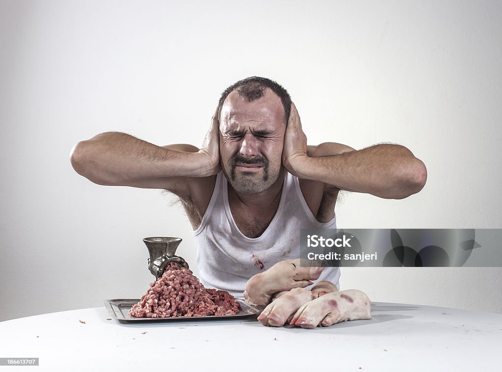 Crazy butcher avec de la viande de porc derrière la table - Photo de Aliment libre de droits