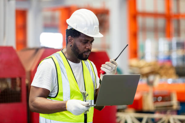 istock African American engineer worker male holding walkie talkie using laptop working in manufacturing factory. technician metalwork automated mechanic energy project. 1866138833