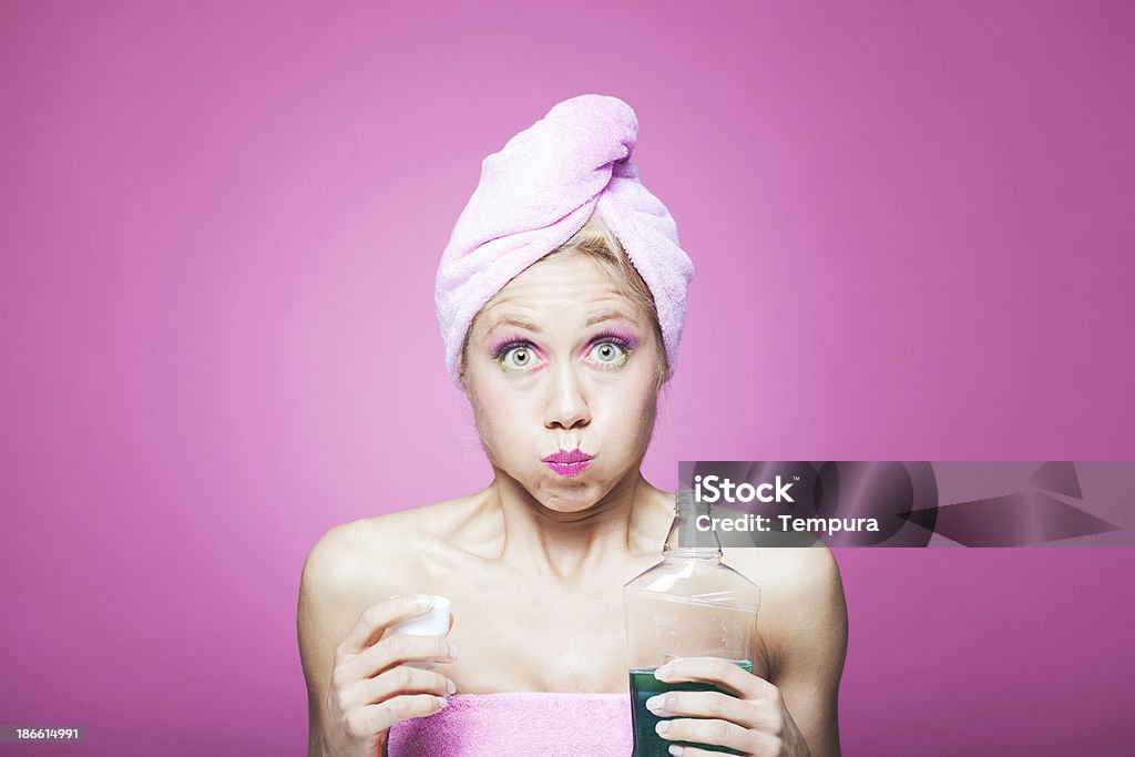 Strong mouthwash troubles_ humor One young woman with mouthwash in the bathroom. More files of this model and series on port. Made with professional make-up and studio equipment. Mouthwash Stock Photo