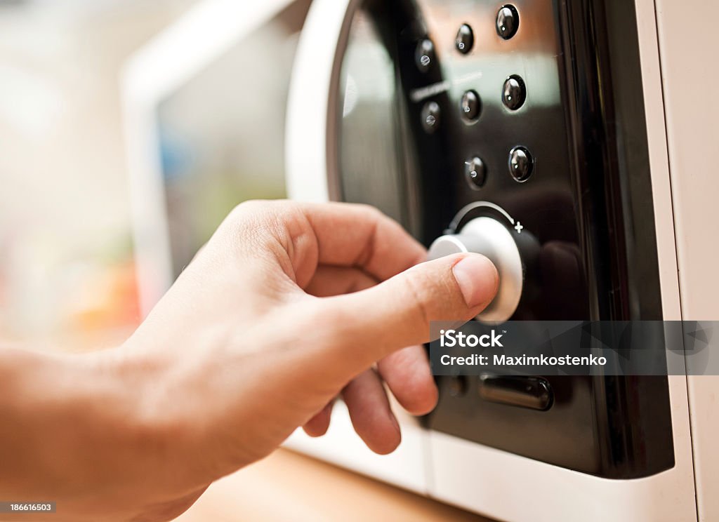 Hand setting the controls on a microwave oven Using microwave oven Appliance Stock Photo