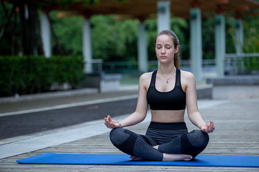 Beautiful women sportswear practicing yoga sitting pose stretching legs and folded hands. Prayer position yoga outdoor on floor. Relaxation yoga exercise concept.