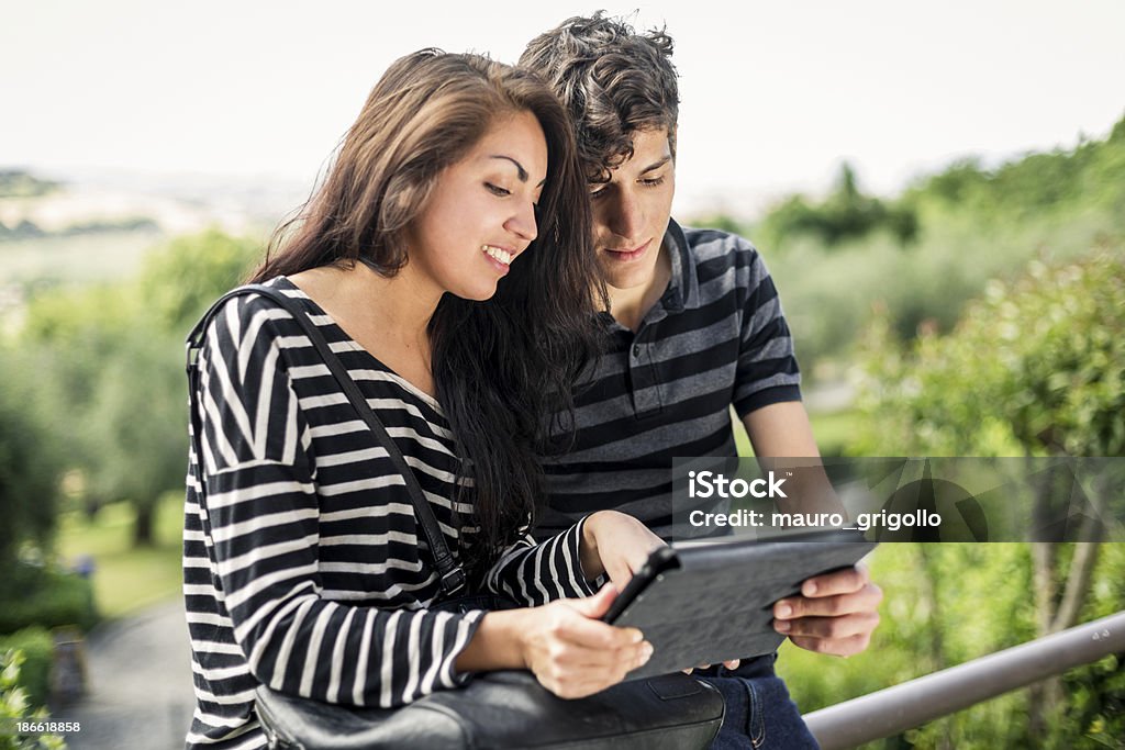 Young couple using a digital tablet Happy young couple using a digital tablet outdoor.  18-19 Years Stock Photo