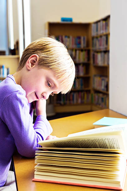istock New reader! Little girl happily absorbed by book in library 186619219