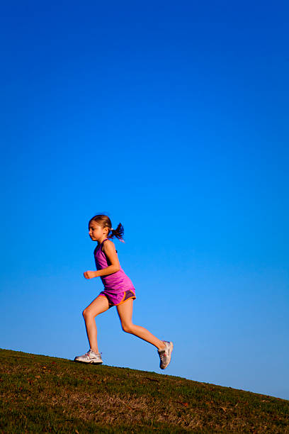 Little girl trail running in the setting sun stock photo