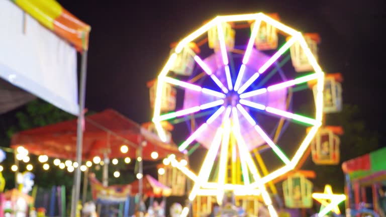 Blurred Ferris wheel spinning in amusement park at night.