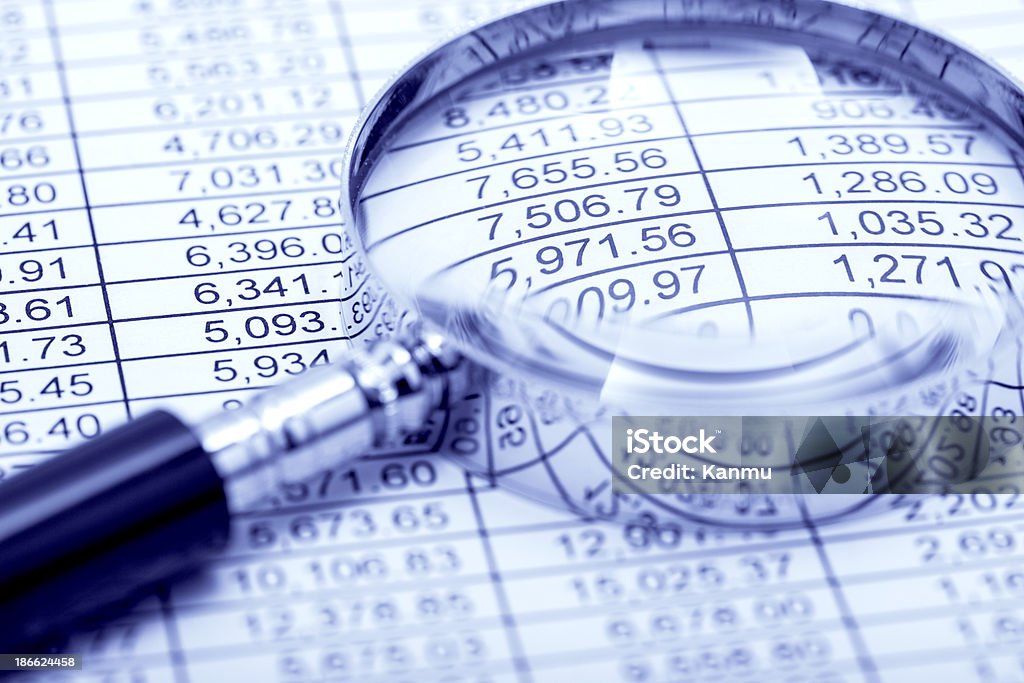 Financial Figures Using a magnifying glass looking at the financial numbers. Analyzing Stock Photo