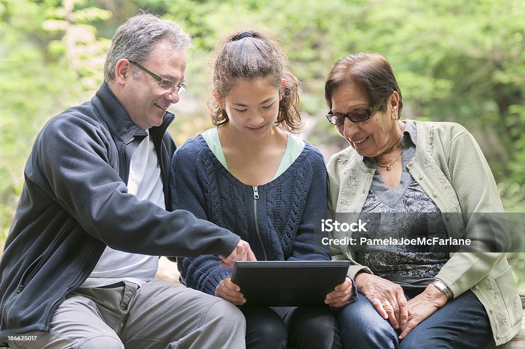 Multi-generacional grupo mirando a la computadora Tablet in Park - Foto de stock de Adolescencia libre de derechos