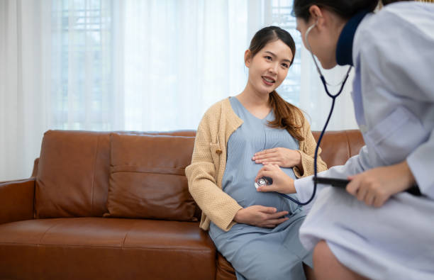 アジアの妊婦は、妊娠コンサルタントのために診療所で婦人科医を訪ねます。医師は妊娠中のお腹を検査し、赤ちゃんと母親の健康診断を受けます。 - abdomen gynecological examination women loving ストックフォトと画像