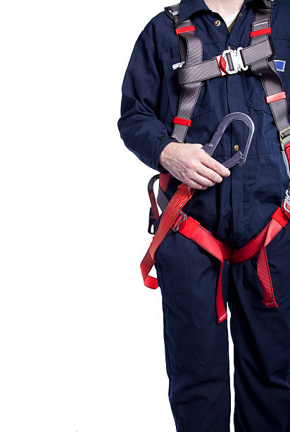 man wearing coveralls and fall protection equipment worker wearing blue coveralls and a fall protection harness and lanyard for work at heights safety harness photos stock pictures, royalty-free photos & images