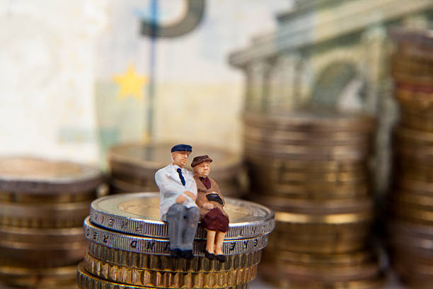 Elderly couple figurine placed on stacks of coins stock photo