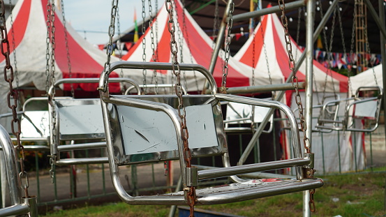 an empty carousel chair, made of stainless steel suspended using several long chains.