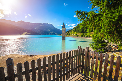 Submerged bell Tower of Curon Venosta or Graun im Vinschgau on Lake Reschen sun haze view, South Tyrol region Italy