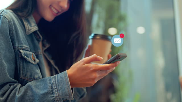 Woman hands using smartphone with 1 new email alert sign icon pop up, Female using phone for check email for work or sending text SMS short message while holding coffee cup at cafe.