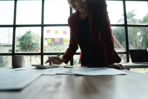istock Business woman behind paper work inside office, female financier worker thinks about contracts and reports with charts and graphs, blonde successful woman uses laptop at work. 1866379807