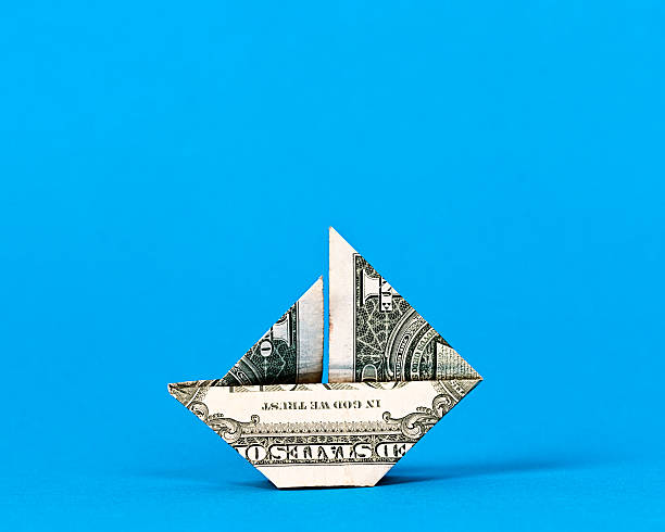 istock Origami sailboat made from US dollar bill on blue 186638693