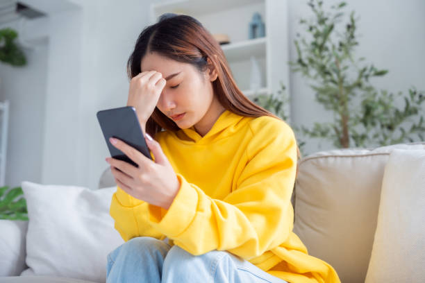 istock Bad news on device screen. Upset asian woman frustrated by problem with work or relationships, sitting on couch, feeling despair and anxiety, loneliness, having psychological trouble 1866475787