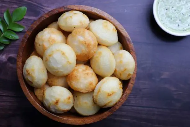 Photo of Paniyaram are savory balls made using fermented rice and urad dal batter along with tempered onion and spices. Also known as Paddu, Ponganalu, Kuli, bugga, and appe. served with coconut chutney