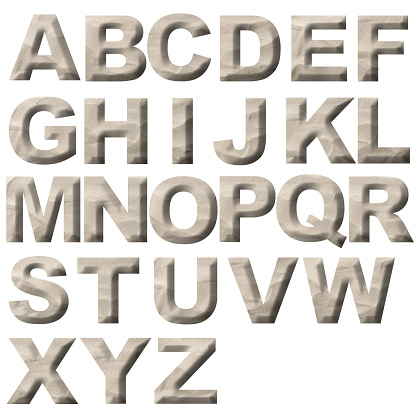 Close-up of three-dimensional sand alphabet on white background.