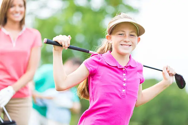 Little girl playing golf with family on country club course