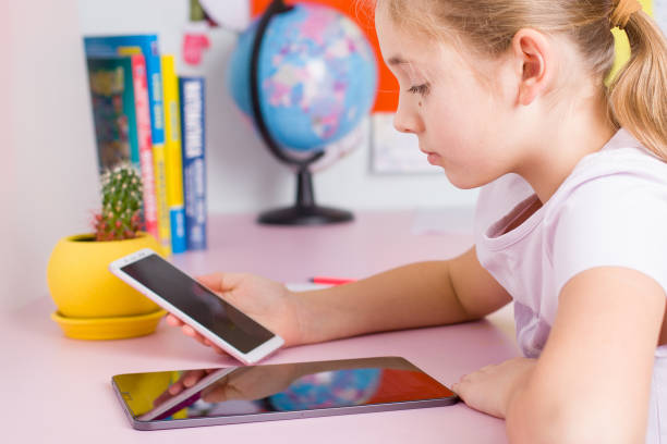 istock Cute little girl using digital tablet while sitting at desk 1866557431