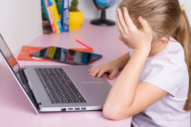 istock The girl studies at the computer and holds her head with her hand. 1866557434