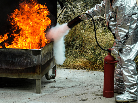 stcw firefighting prevention training, man using fire extinguisher against open fire in a barrel, maritime courses