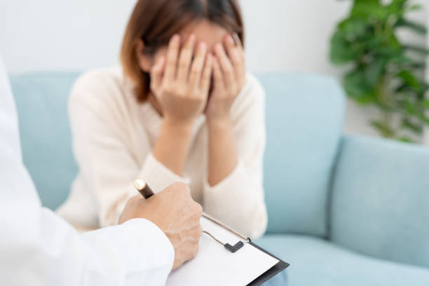 メンタルヘルスに問題のある女性が相談しています。精神科医は治療のために患者の状態を記録しています。励まし、愛と家族の問題、双極性障害、うつ病患者、自殺を守る - うつ病 ストックフォトと画像