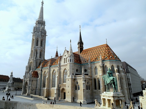 The Matthias Church with its beautiful tiled roof and an equestrian statue in Budapest, Hungary