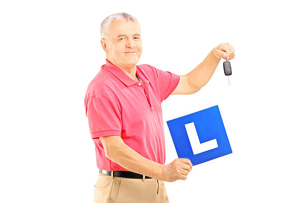 istock Smiling senior man holding a L plate and car key 186661977