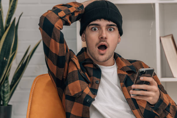 istock young man at home with mobile phone and surprised expression 1866636416